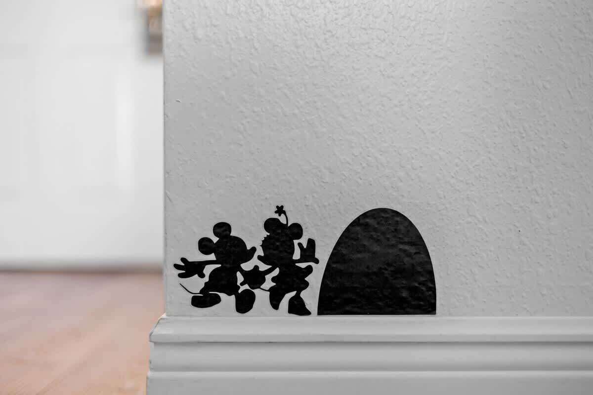Paredes brancas com silhuetas negras de três figuras e um formato semicircular.