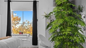 Una camera moderna con un letto, una scrivania, una sedia, una pianta in vaso e una finestra con tende.
