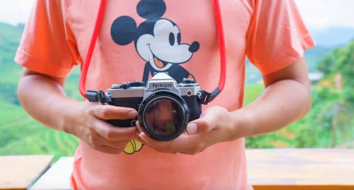 A person holding a Nikon camera.