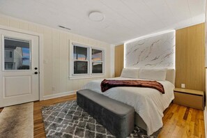 Ein Schlafzimmer mit einem Bett, einer Bank, einem Fenster und einer Marmorwand.