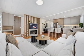 Uma sala de estar moderna com televisão, sofá, mesa de centro e área de cozinha.