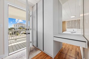 Une salle de bain moderne avec une douche à l’italienne en verre, un meuble-lavabo blanc et une vue sur un quartier résidentiel.