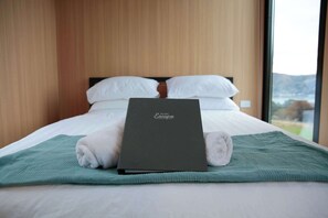 Una cama con una computadora portátil, almohadas y vistas al exterior.