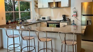 A modern kitchen with a central island, bar stools, stainless steel appliances, and pendant lighting. - house with a beautiful sea view in enchanting SurfCity with WiFi, AC and Pool. (La Libertad)
