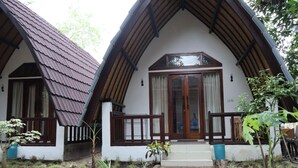 A traditional chalet with a steeply pitched roof, wooden balcony railings, and a central entrance with a glass door.