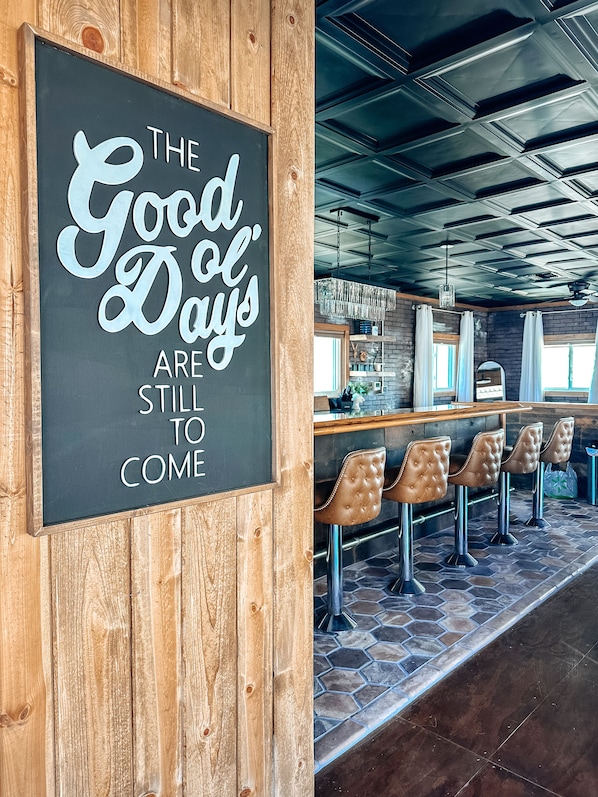 A bar area with a chalkboard sign, wooden paneling, and hexagonal tile flooring.