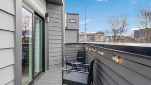 A balcony with two chairs and string lights.
