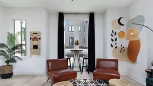 A modern living room with two leather sofas, a coffee table, and a large window with curtains.