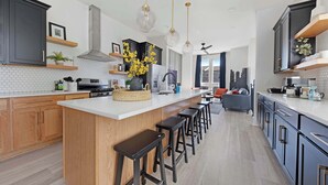 A modern kitchen with a central island, bar stools, and pendant lighting.