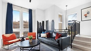A modern living room with a black leather sofa, red armchair, and a round coffee table.