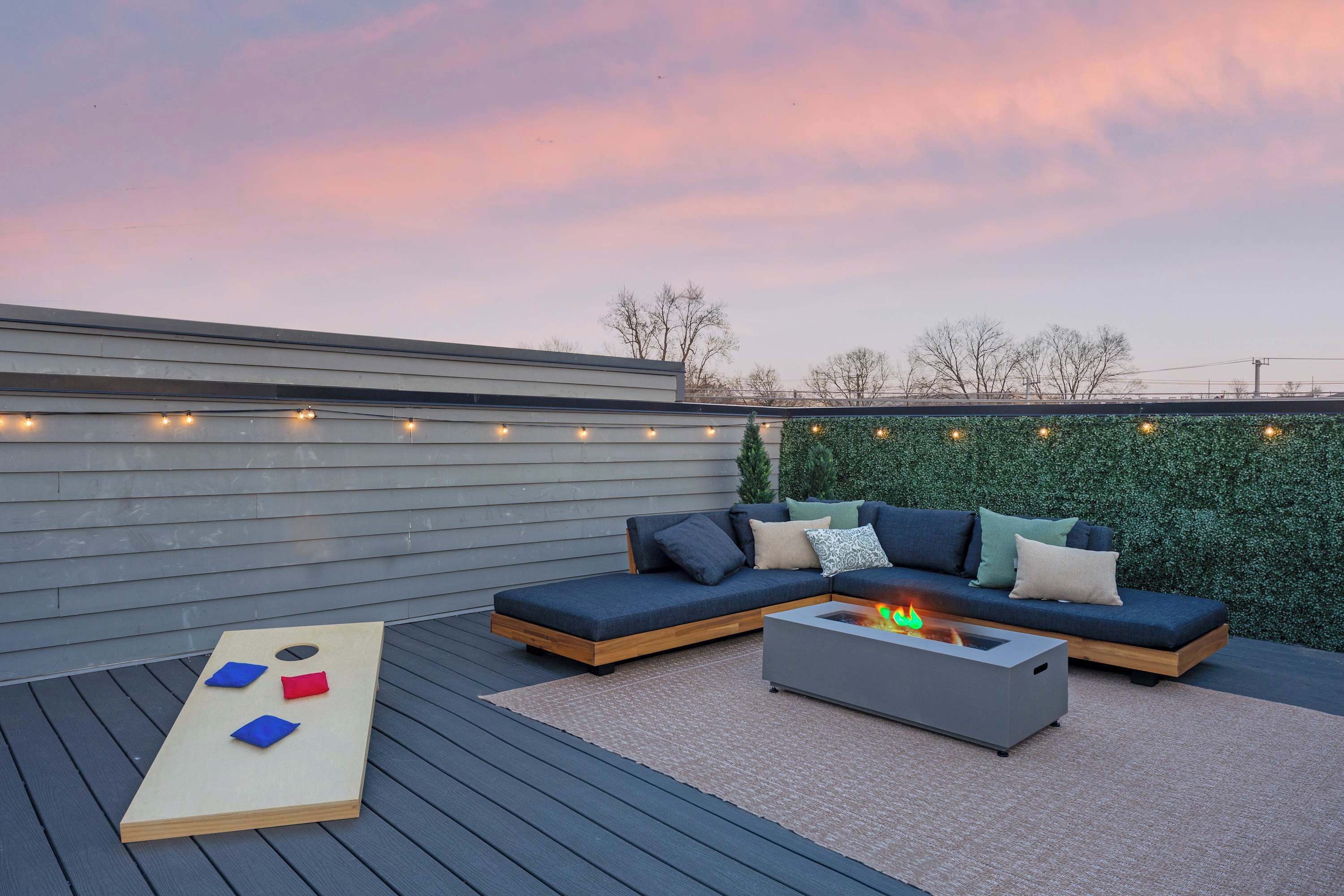 A rooftop deck with a sectional sofa, a fire pit, and a board game.