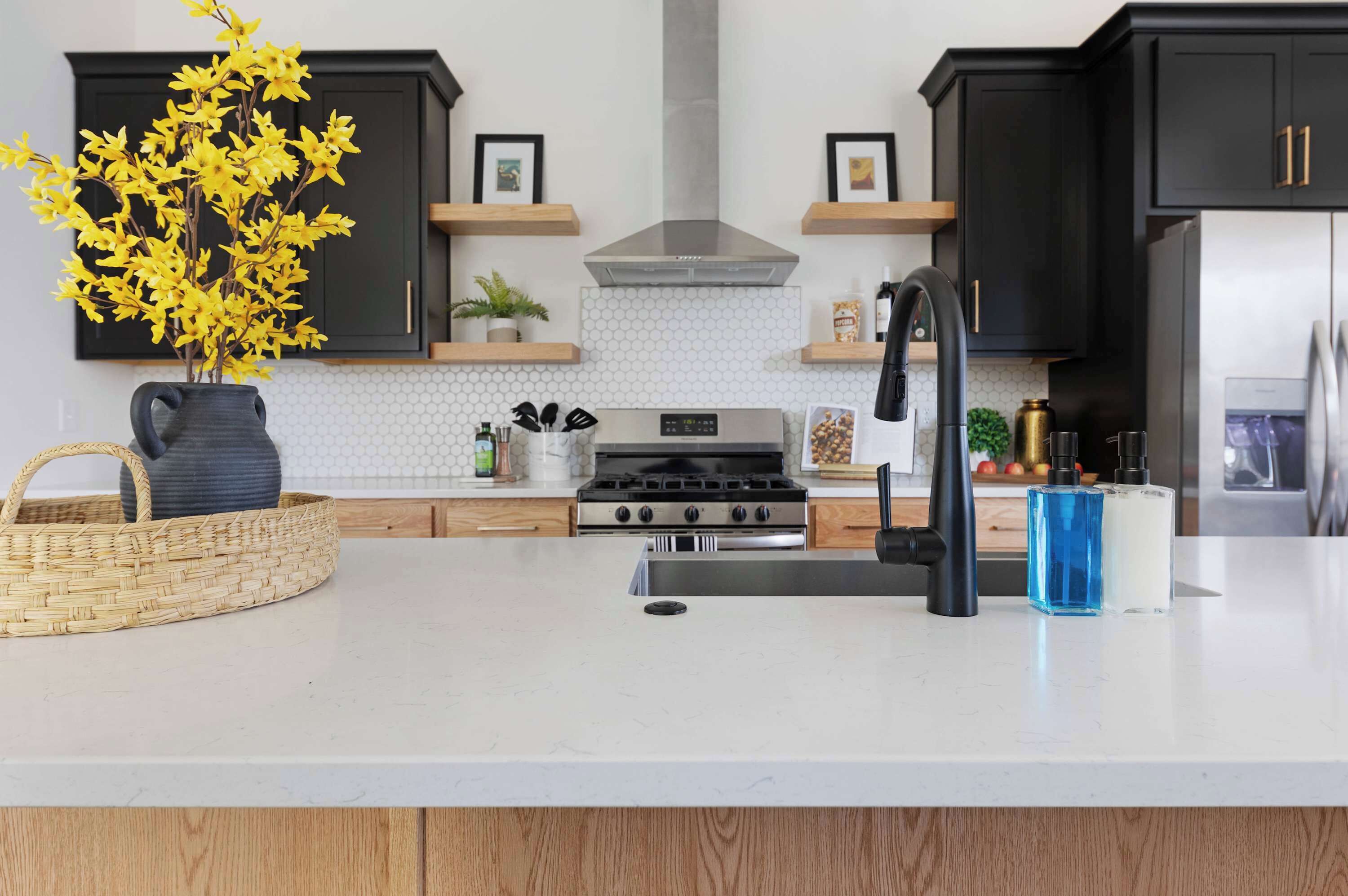 A modern kitchen with dark cabinets, a stainless steel stove, and a white countertop.
