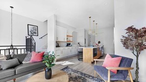 A modern living room with a sofa, coffee table, and a dining area. - Camellia | Rooftop & Pet-Friendly Stay (Nashville)