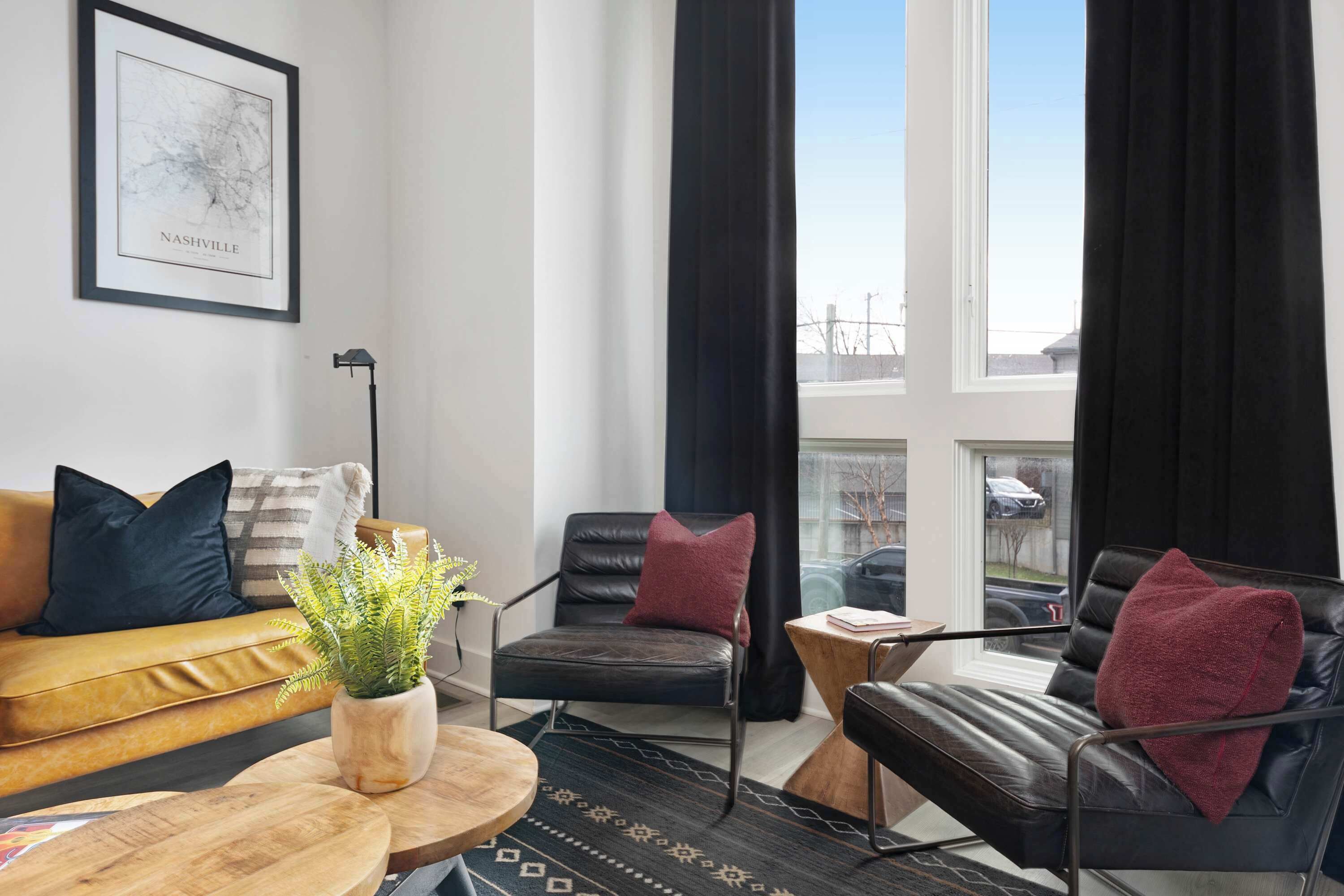 Un salon moderne avec un canapé, deux fauteuils, une table basse et une plante en pot.