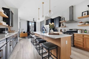 A modern kitchen with a large island, bar stools, and pendant lighting. - The Bluestem - Stylish Design, Rooftop w/ Firepit! (Nashville)