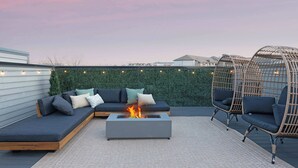 A rooftop patio with a fire pit, a sectional sofa, and wicker chairs. - The Bluestem - Stylish Design, Rooftop w/ Firepit! (Nashville)
