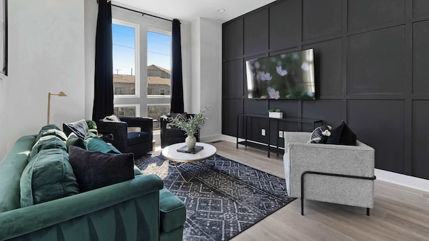 A modern living room with a sofa, armchair, and a TV mounted on the wall.