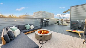 A rooftop patio with a fire pit, outdoor seating, and a view of the city skyline.