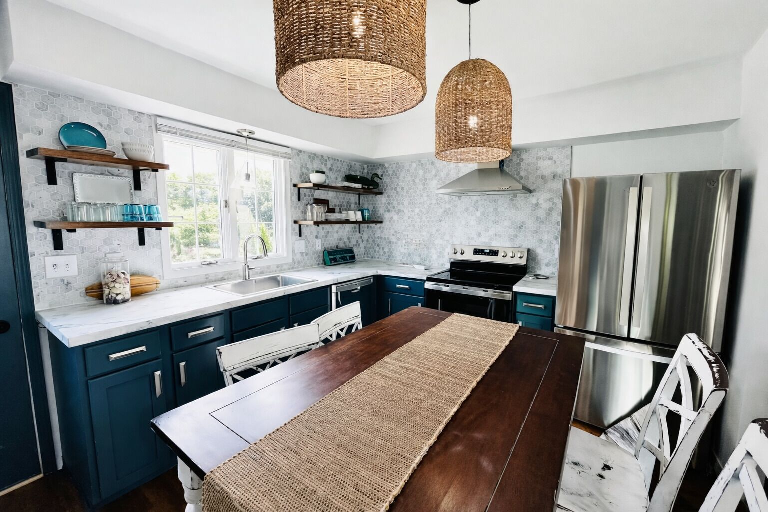Une cuisine moderne avec des meubles de couleur bleu foncé, une table à manger en bois et une grande fenêtre.