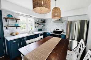 Una cocina moderna con armarios azul oscuro, una mesa de comedor de madera y un ventanal.