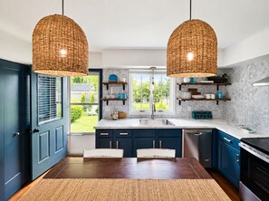 A modern kitchen with dark blue cabinets, a white countertop, and a large window.