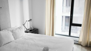 A hotel room with a large bed, a bedside table with a lamp, and a window with curtains.