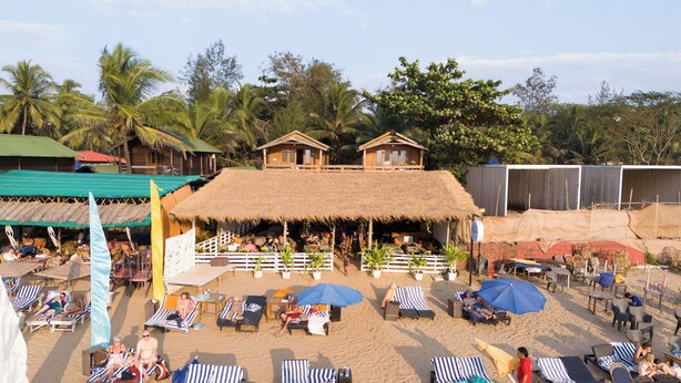 A beach resort with thatched-roof huts, lounge chairs, and umbrellas. - Aquila Boutique Resort Agonda (Canacona)