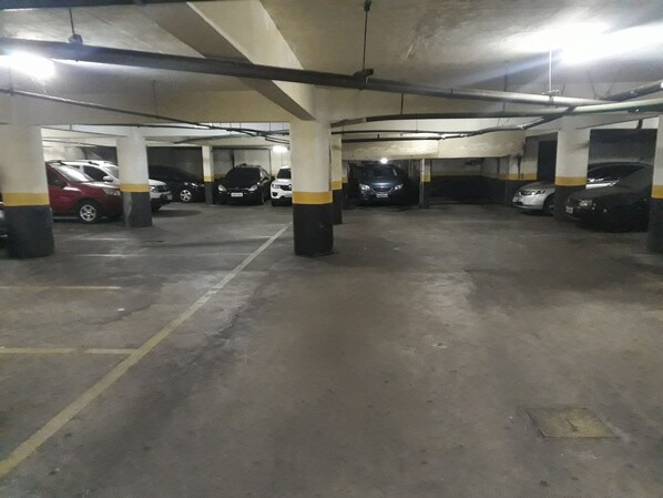 Un estacionamiento subterráneo de varios niveles, con pilares de hormigón y vigas sobre la cabeza.
