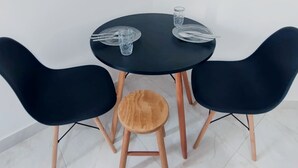 Ein runder schwarzer Tisch mit zwei schwarzen Stühlen und einem hölzernen Hocker.
