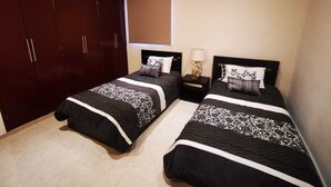 A bedroom with two beds, dark wooden wardrobe, and an air conditioning unit. - Charming 3-bedroom house with Private Pool in lovely Cancun (Cancun)