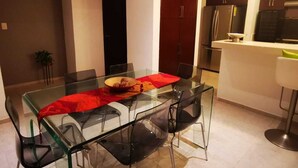 A modern kitchen with a glass dining table, black chairs, and stainless steel appliances. - Charming 3-bedroom house with Private Pool in lovely Cancun (Cancun)