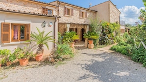 A courtyard with stone buildings, potted plants, and gravel paths. - Can Ventet by SunVillas Mallorca (Pollença)