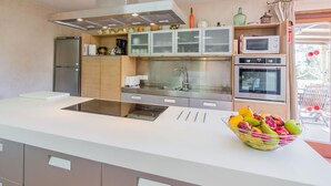 A modern kitchen with a central island, stainless steel appliances, and a fruit bowl. - Can Ventet by SunVillas Mallorca (Pollença)