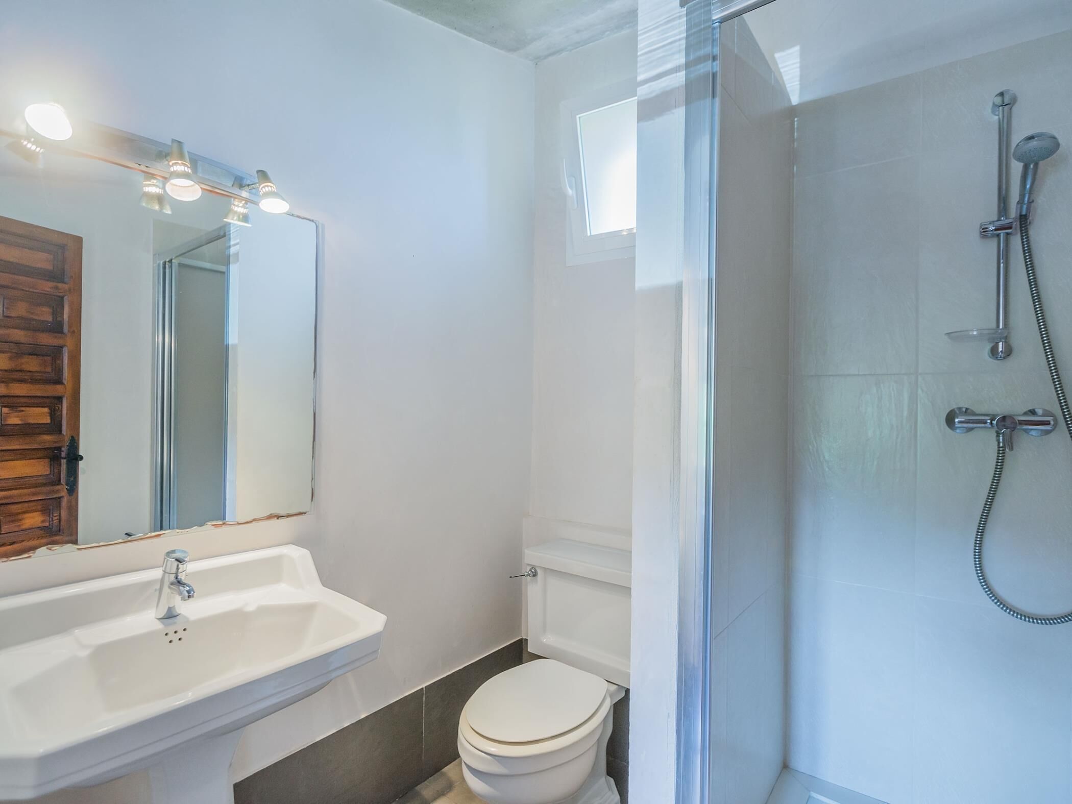 A modern bathroom with a glass shower enclosure, a white sink, and a toilet.