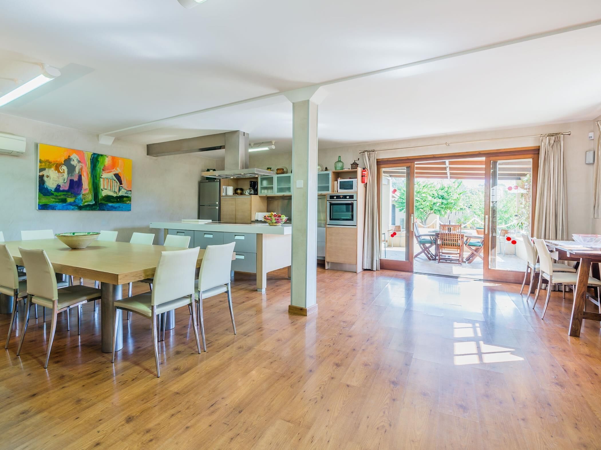 Amplia sala de estar con mesa de comedor, cocina y puertas de vidrio correderas que dan a un patio exterior.