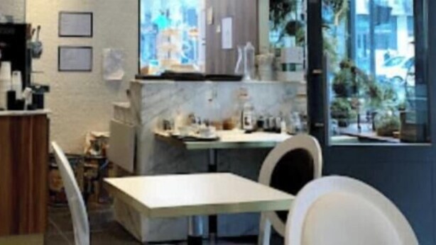 Un café moderne avec un comptoir en marbre, une machine à café et une vue sur la ville grâce à de grandes fenêtres.