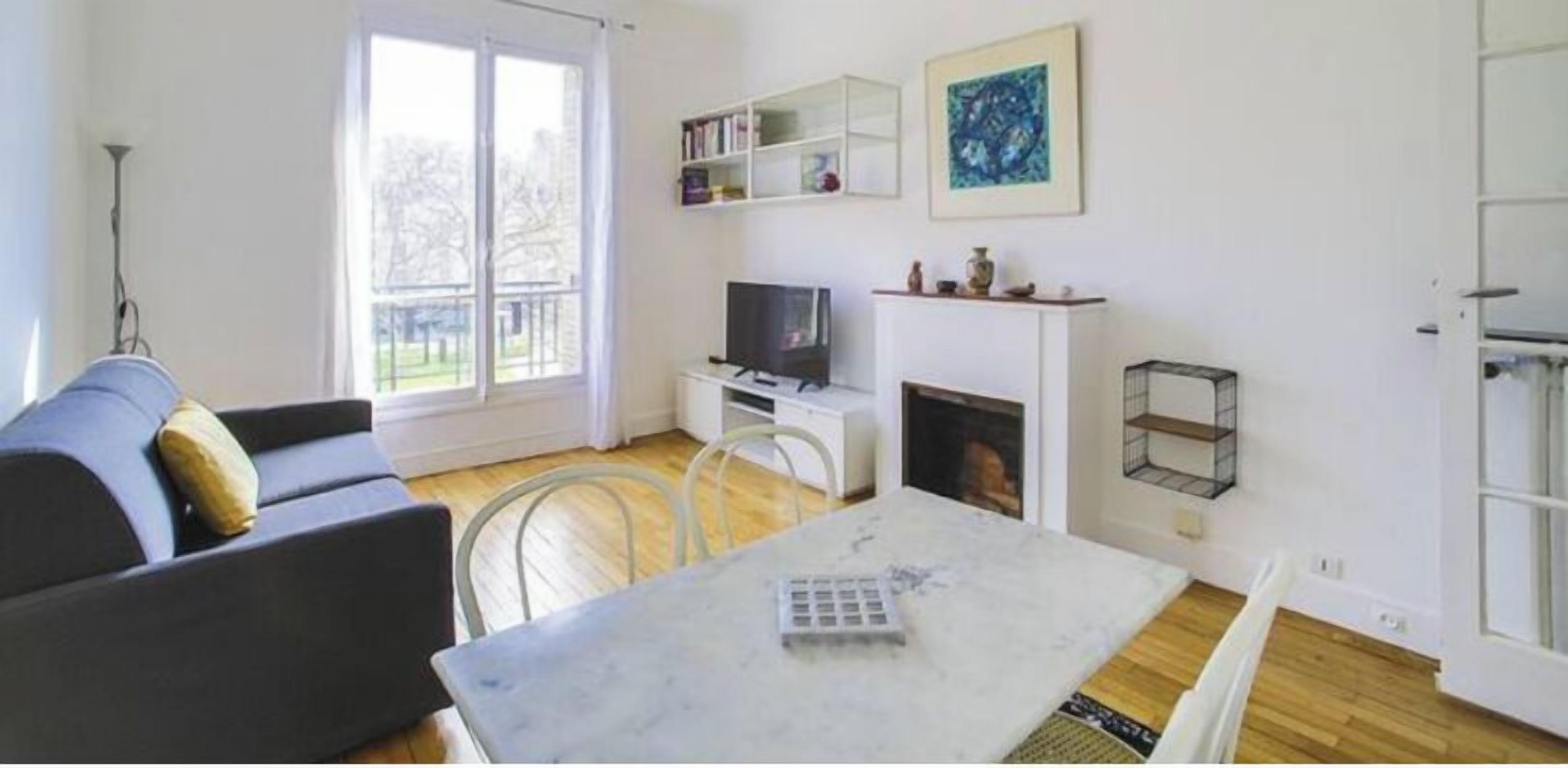 Una sala de estar con sofá, televisión, chimenea y mesa de comedor.