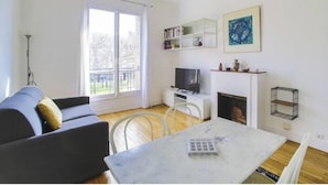 Un salon comprenant un canapé, un téléviseur, une cheminée et une table à manger.