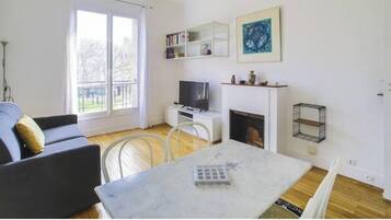 Una sala de estar con sofá, televisión, chimenea y mesa de comedor.