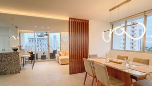 Un comedor moderno con una mesa de madera, sillas acolchadas y vistas a la ciudad a través de amplias ventanas.
