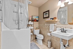 Une salle de bain équipée d’une baignoire, de toilettes, d’un lavabo et d’une douche.