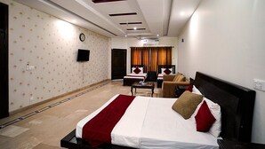 A hotel room with a bed, a desk, a chair, a TV, and a window with curtains. - Capri Inn Guest House (Islamabad)