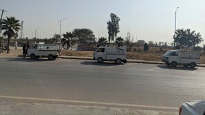 A street with multiple white pickup trucks parked on the side. - Capri Inn Guest House (Islamabad)