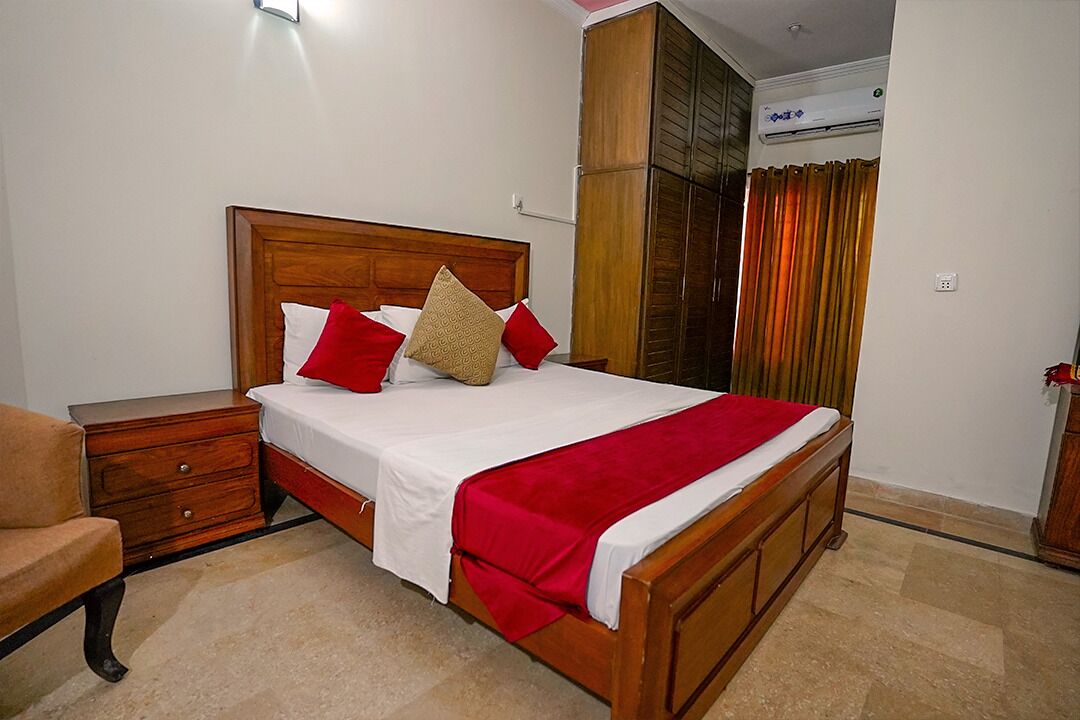 A neatly arranged bedroom with a wooden bed, a nightstand, a chair, and a wardrobe.