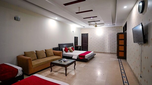 A hotel room with a sofa, a bed, a TV, and a ceiling fan. - Capri Inn Guest House (Islamabad)