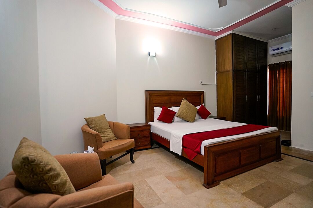 A bedroom with a wooden bed, a nightstand, a chair, and a wardrobe.