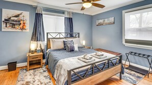 A bedroom with a bed, nightstands, a ceiling fan, and artwork on the walls.