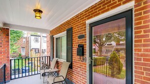 A covered porch with a brick wall, a sliding glass door, and outdoor furniture.