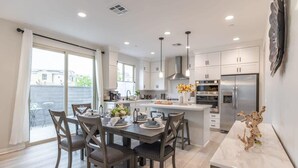 A modern kitchen with white cabinets, a central island, and stainless steel appliances. - @marbella Lane -amazing 5BR Home in Rancho Mission (San Juan Capistrano)