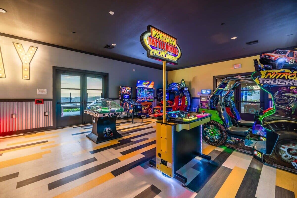 Un salón de juegos con letreros de neón para Pac-Man, Battle Royale y Nitro Trucking.